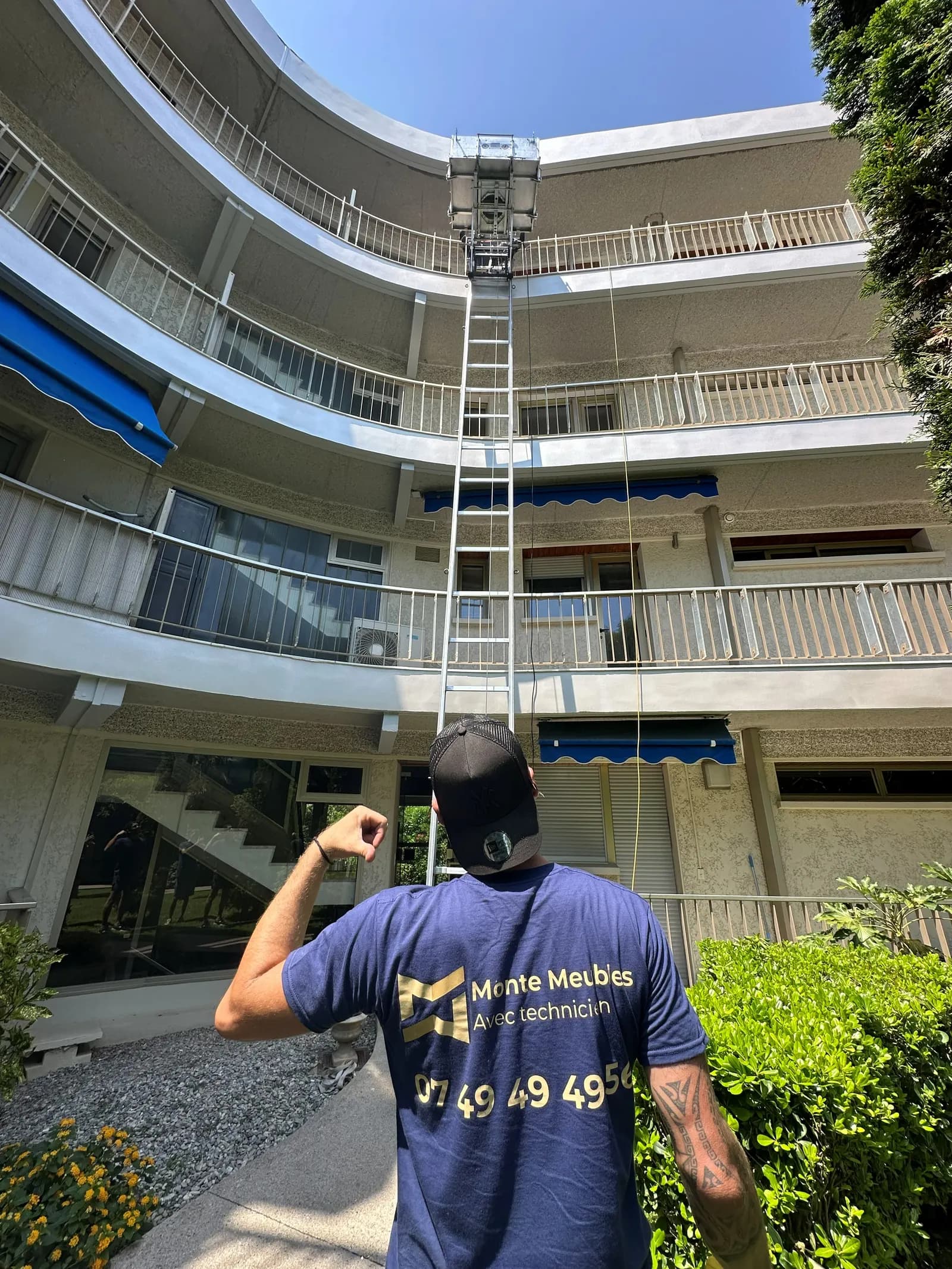 Technicien pilotant un monte-meuble depuis le sol dans une cour intérieure